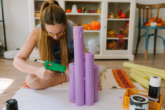 Woman using a glue gun for a Halloween DIY