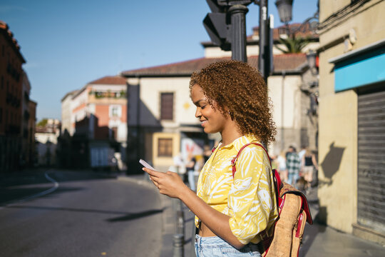 Woman waiting at a pedestrian crossing using smartphone