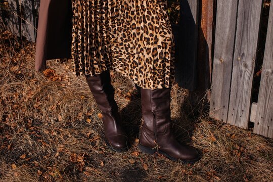 Anonymous woman in leather boots and leopard pattern skirt