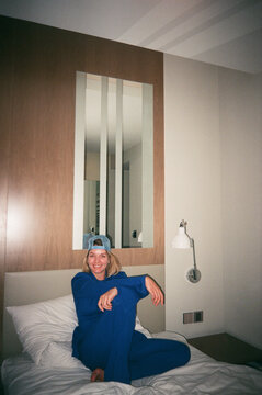 Cheerful woman with snapback cap sitting on cozy bed