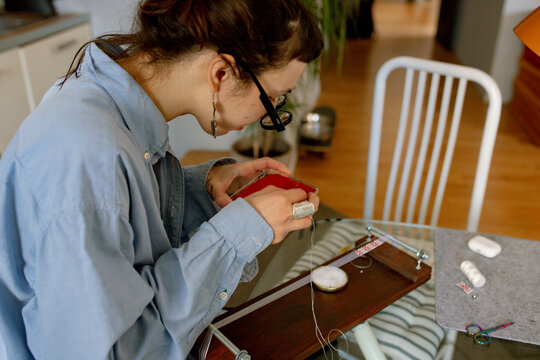 a woman weaves a bracelet from beads
