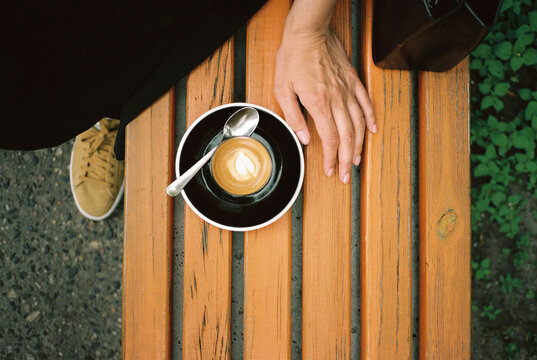 Hand and cup of coffee on a bench