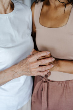 Crop senior mother and adult daughter holding hands