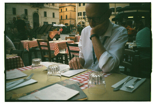 Senior businessman with menu at outdoor Rome restaurant