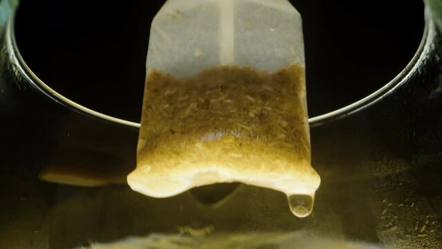 Macro view from the glass, the tea bag is lifted upwards.