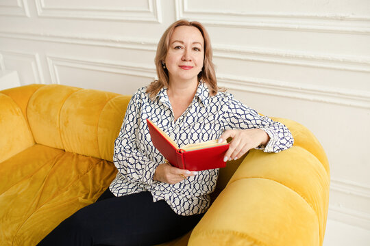 Woman with red notebook sitting on the sofa 