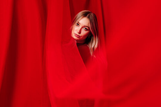 Charming fair haired lady in split of hanging red cloth