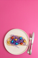 Sandwich with hay and Easter eggs in a plate on a pink background.