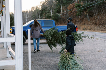 family with grandmother loading up Christmas tree in truck