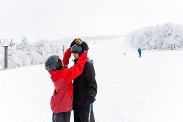 Fototapeta na wymiar Happy Asian people enjoy outdoor active lifestyle winter extreme sport training on holiday vacation. Man and woman athlete practicing freeride snowboarding and ski at ski resort on snowy mountain.