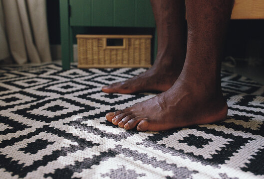 Man's barefoot by the bed