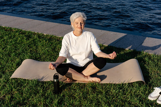 Senior woman doing yoga on lawn