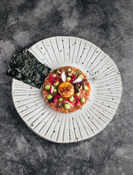 Appetizing tartare topped with egg yolk on plate