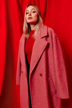 Stylish woman in red coat looking at camera in studio