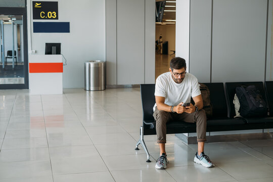 Handsome Man Sitting at Airport and Waiting for Flight