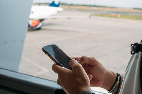 Cropped Image of Hands Holding Mobile Phone at Airport 
