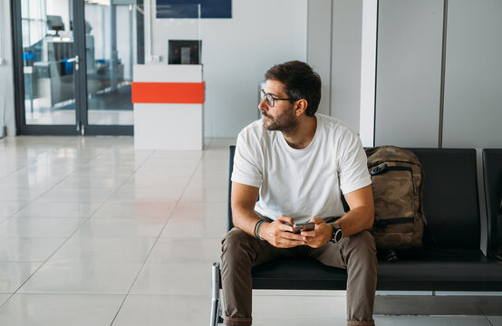 Handsome Man Sitting at Airport and Waiting for Flight