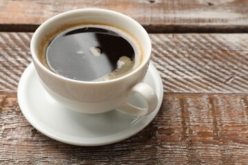Cup of aromatic coffee on wooden table, closeup. Space for text
