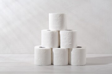 Pyramid of toilet paper rolls on white wooden table
