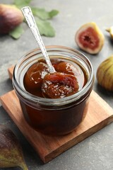 Jar of tasty sweet fig jam on grey table