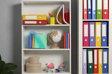 Colorful binder office folders and other stationery on shelving unit indoors