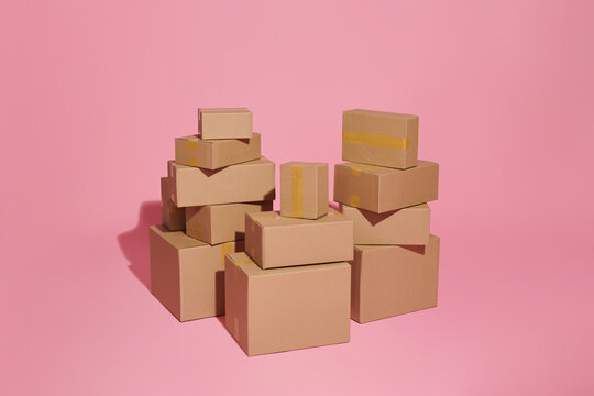 Cardboard boxes of different sizes on a pink background.