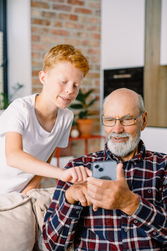 Grandfather and grandson use mobile at home