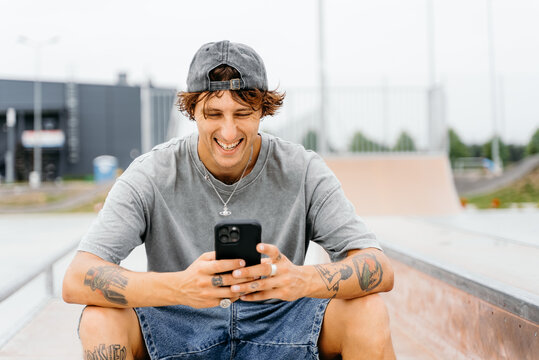A man uses a mobile phone while sitting in a skate park