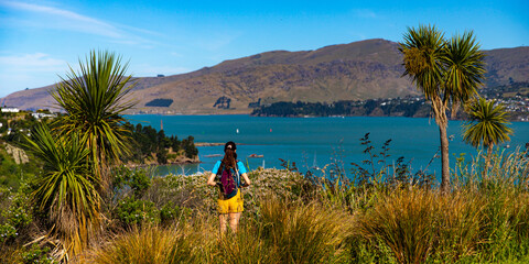 pretty backpacker girl enjoys the coastal walk between pony point and lyttelton near christchurch,...