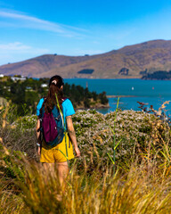 pretty backpacker girl enjoys the coastal walk between pony point and lyttelton near christchurch,...