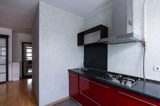 Open empty studio kitchen with modern red furniture and tiled wall