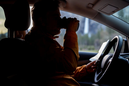 A Man Drinks From A travel Cup While looking at a map
