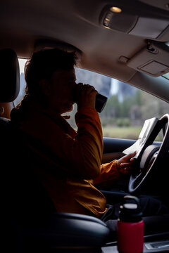 A Man Drinks From A travel Cup While looking at a map