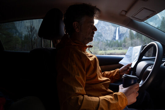 A Man Drinks From A travel Cup While looking at a map
