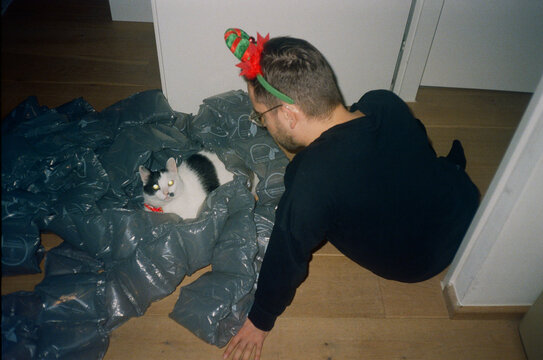 A man looking at his cat lying on packaging air bags