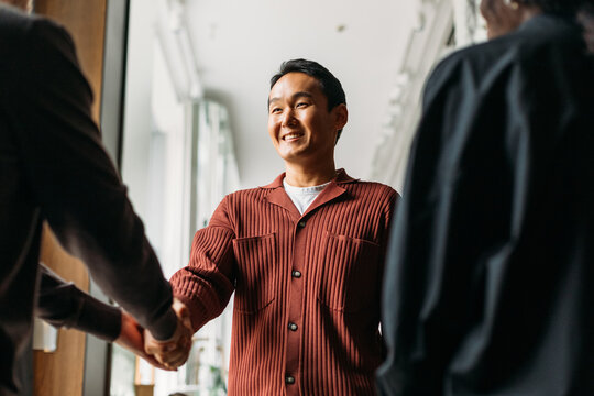 Asian guy greeting with people in cafe