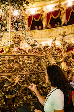 A girl screws a light bulb into an antique chandelier in the theater