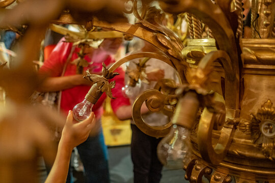 A hand screws a light bulb into a luxurious classic chandelier