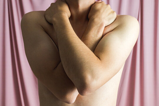 Close up of the naked torso of a young man with his arms crossed