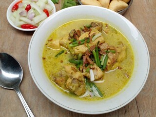 Gulai ayam or chicken curry served in a white bowl. A soupy dish made from chicken cooked with spices and coconut milk. Indonesian traditional cuisine.