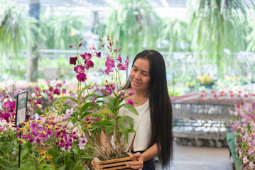 Happy Beautiful young woman in a flower shop and choosing flowers. The concept of gardening and flowers .