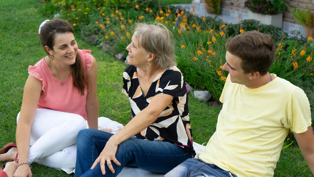 two adult children with their mother sitting in the garden