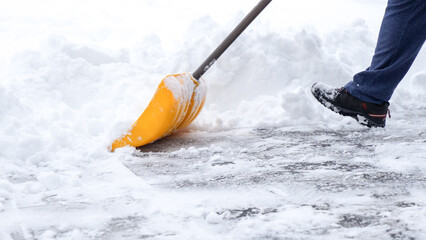 Man shoveling snow off of his driveway after a winter storm in Canada. Man with snow shovel cleans...