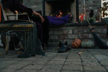 weary witch relaxes without shoes by fireplace
