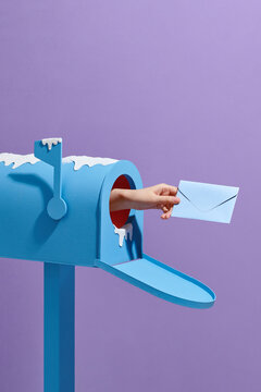 Hand-sending letter out of a mailbox with snow