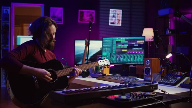 Artist playing guitar and uses DAW software interface to create music, looking at mastering controls on computer screen. Musician recording soundtracks with tools, acoustical engineering. Camera B.