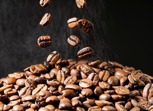 High-contrast image of coffee beans being dropped onto a pile
