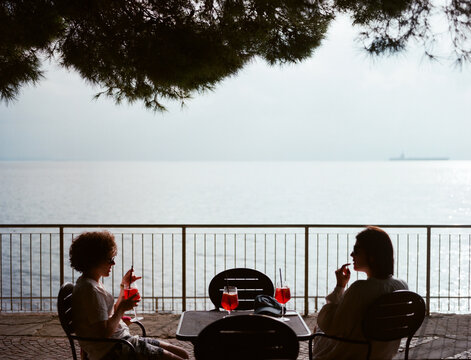 Female friends with a cocktail chilling by the sea 