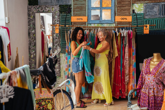 Happy women choosing dress in store shop