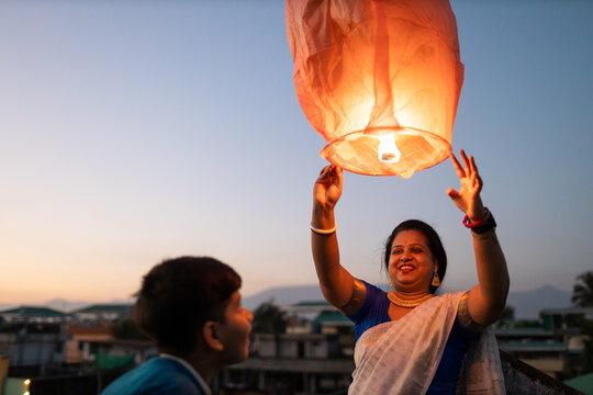 Mother and son releasing sky lantern at twilight